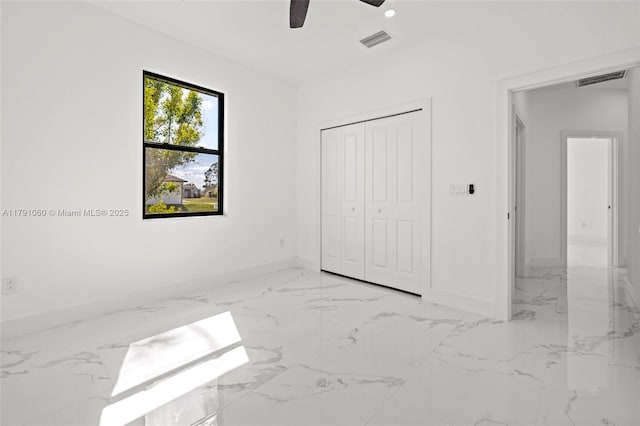 unfurnished bedroom featuring marble finish floor, visible vents, a closet, and baseboards