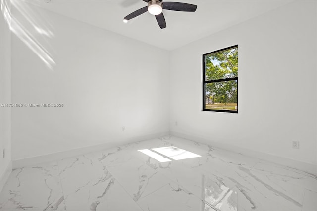 spare room with baseboards, ceiling fan, and marble finish floor