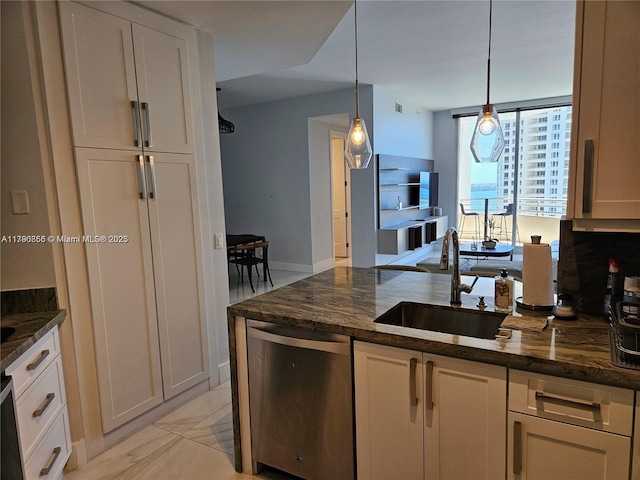 kitchen with stainless steel dishwasher, hanging light fixtures, dark stone counters, a sink, and a peninsula