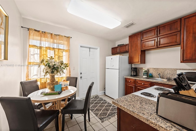 kitchen featuring a sink, freestanding refrigerator, light tile patterned floors, a toaster, and visible vents