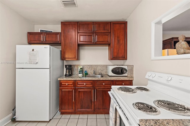 kitchen with a sink, white appliances, light tile patterned floors, reddish brown cabinets, and visible vents