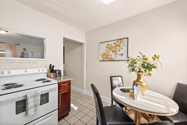kitchen with baseboards, light countertops, white range with electric stovetop, and light tile patterned flooring