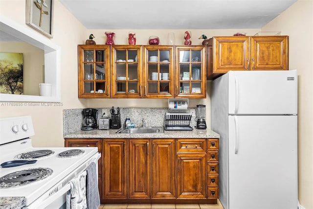kitchen with white appliances, brown cabinets, glass insert cabinets, and a sink