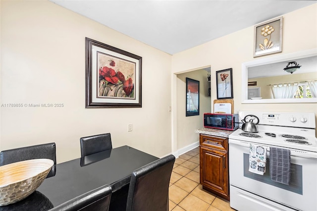 kitchen featuring light tile patterned floors, baseboards, and white electric stove