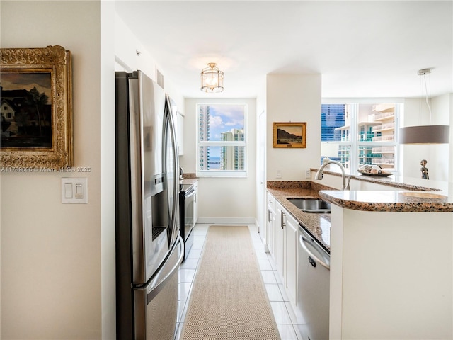 1155 Brickell Bay Dr Unit 2101, Miami, FL 33131 - kitchen with dark stone countertops, light tile patterned floors, white cabinets, a sink, and stainless steel appliances