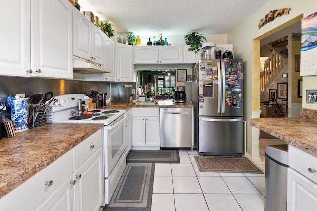 kitchen featuring white cabinets, stainless steel appliances, light tile patterned flooring, and under cabinet range hood