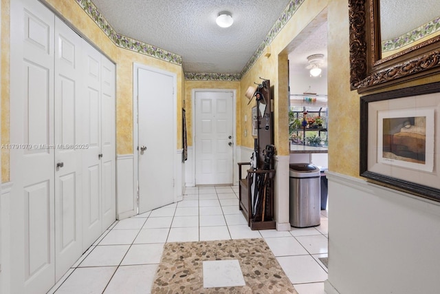 corridor featuring a textured ceiling and light tile patterned flooring