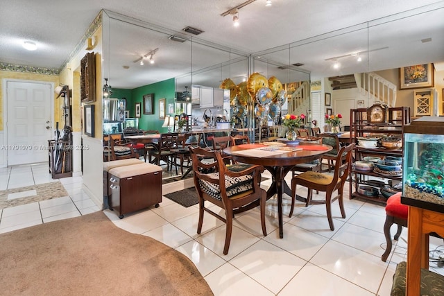 dining room with track lighting, light tile patterned floors, visible vents, and stairs