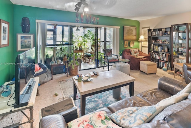 carpeted living area with a wealth of natural light, a ceiling fan, and a textured ceiling