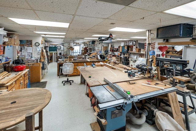 miscellaneous room with tile patterned floors, a workshop area, and a drop ceiling