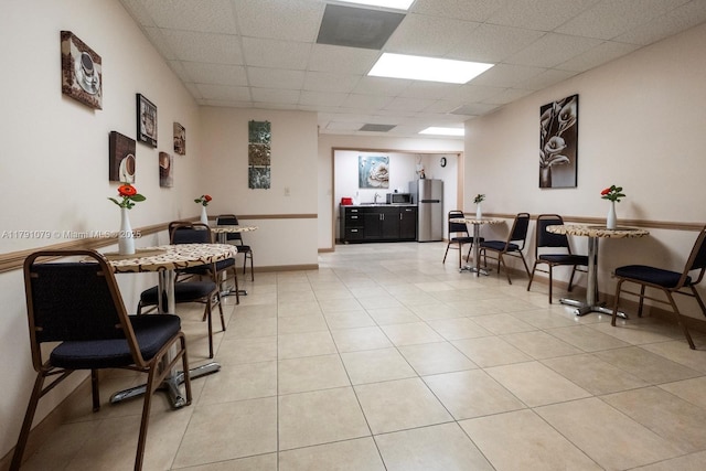 dining area featuring light tile patterned floors and a drop ceiling