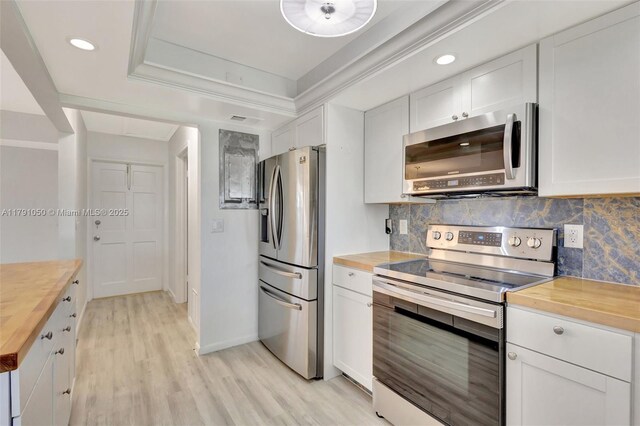kitchen with butcher block counters, tasteful backsplash, and stainless steel appliances