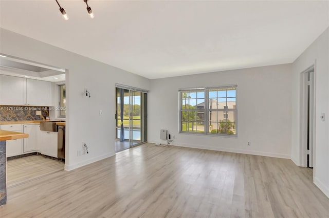 unfurnished living room featuring baseboards and light wood finished floors