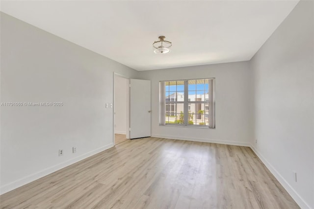 spare room with baseboards and light wood-type flooring