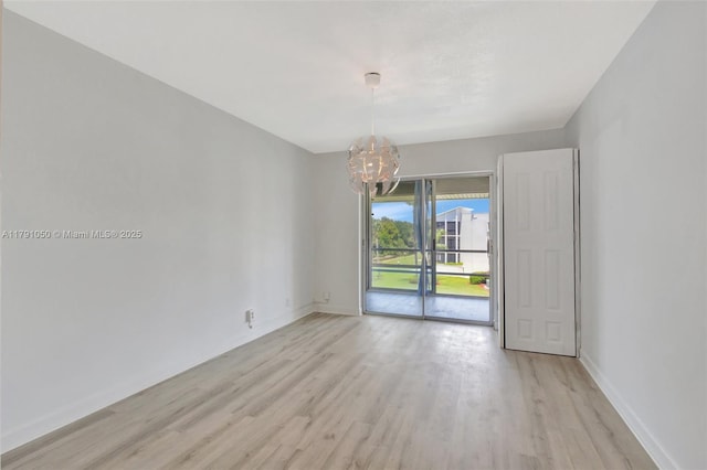 empty room featuring baseboards, light wood finished floors, and a chandelier