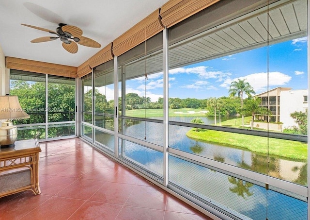 unfurnished sunroom with a water view, tile patterned flooring, and ceiling fan