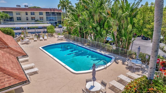 community pool with fence and a patio area