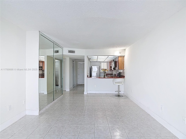 unfurnished living room with a textured ceiling and light tile patterned flooring