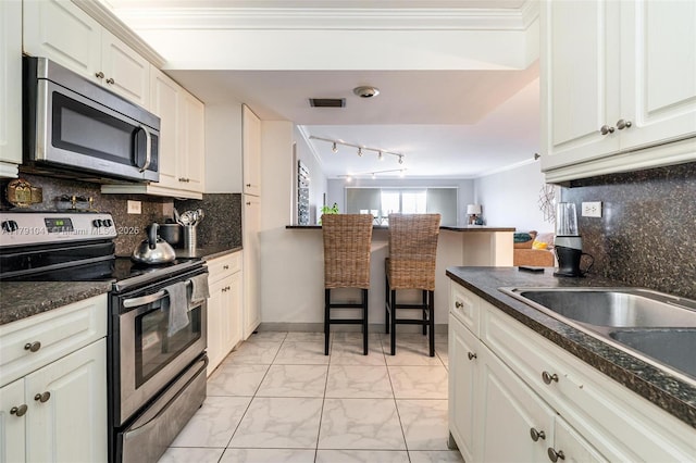 kitchen with tasteful backsplash, marble finish floor, visible vents, dark countertops, and appliances with stainless steel finishes