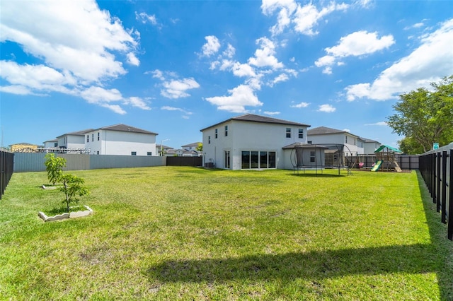 view of yard featuring a trampoline, a playground, and a fenced backyard