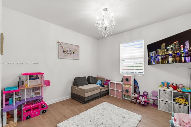 game room featuring an inviting chandelier, wood finished floors, and baseboards