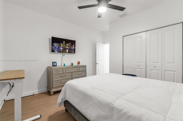 bedroom featuring a closet, light wood finished floors, baseboards, visible vents, and a ceiling fan