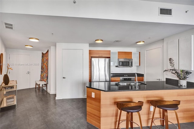 kitchen with a breakfast bar area, visible vents, stainless steel appliances, and dark countertops