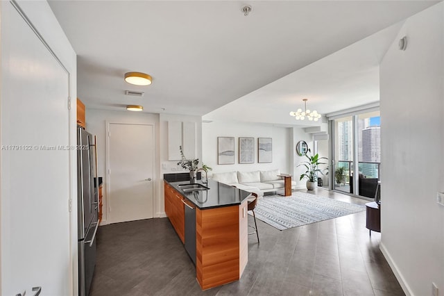 kitchen featuring a chandelier, appliances with stainless steel finishes, a sink, a peninsula, and open floor plan