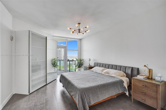 bedroom featuring floor to ceiling windows, a chandelier, wood finished floors, and access to exterior