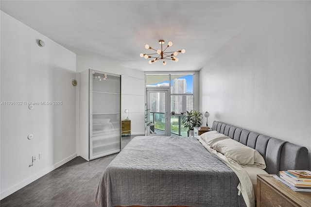 bedroom featuring wood finished floors, expansive windows, a notable chandelier, and baseboards