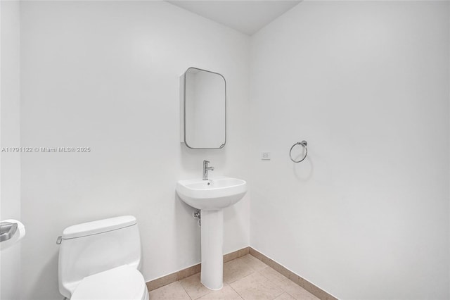 half bathroom featuring baseboards, toilet, and tile patterned flooring