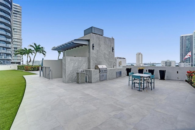 view of patio featuring outdoor dining area, a sink, area for grilling, a view of city, and grilling area