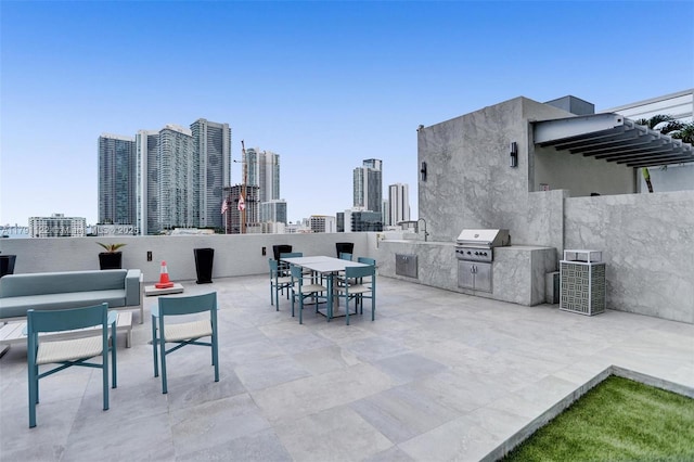 view of patio / terrace with a city view, outdoor dining area, a grill, and exterior kitchen