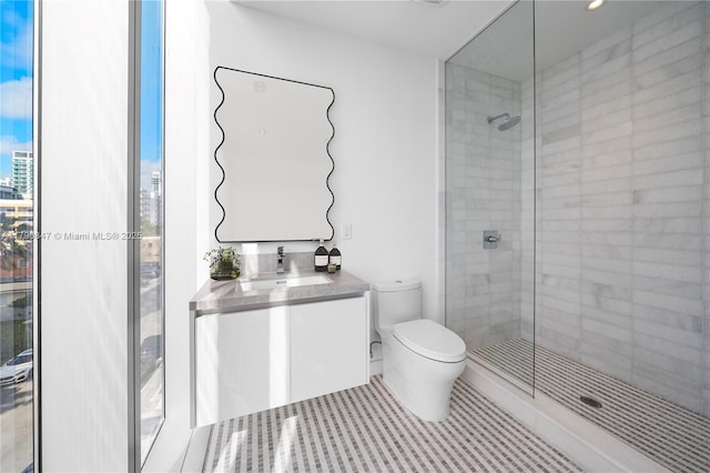 bathroom with toilet, tile patterned floors, tiled shower, and vanity