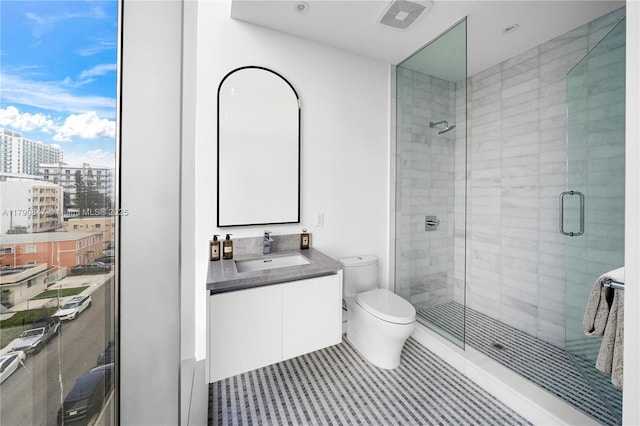 bathroom featuring toilet, visible vents, a shower stall, and vanity