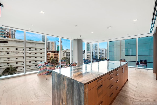 kitchen with a spacious island, stone counters, a city view, and brown cabinetry