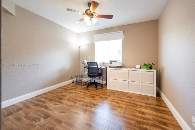 office area featuring baseboards, a textured wall, a ceiling fan, and wood finished floors