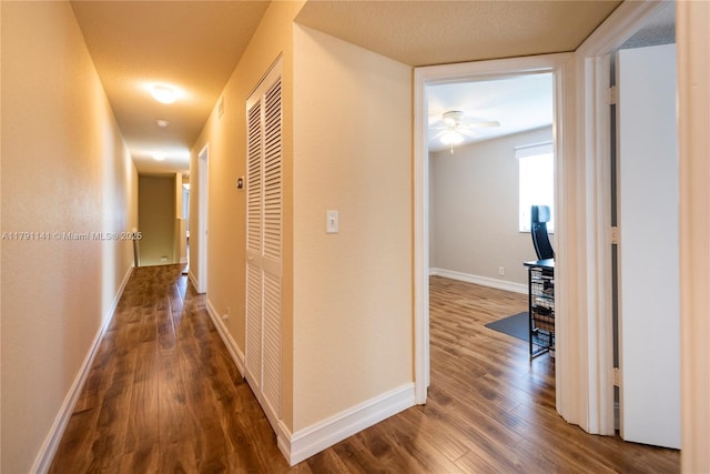 hall featuring baseboards, wood finished floors, and visible vents