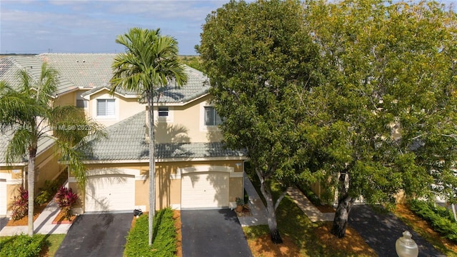 view of property with an attached garage, aphalt driveway, a tile roof, and stucco siding