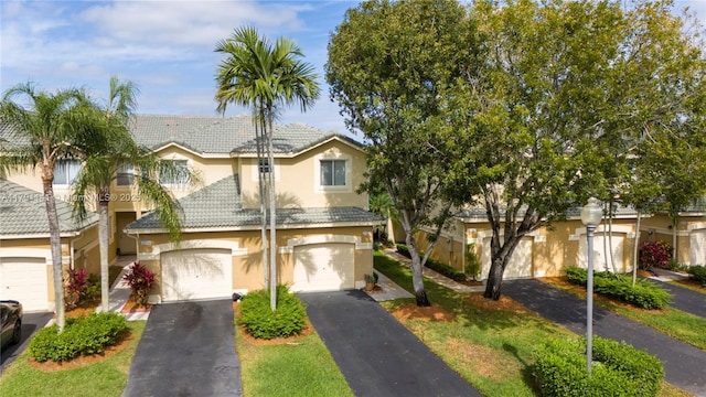 view of front of home with a tiled roof, a garage, aphalt driveway, and stucco siding
