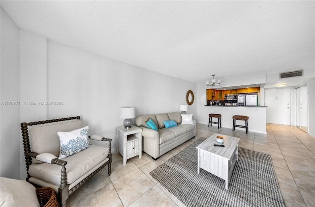 living room featuring an inviting chandelier, light tile patterned floors, and visible vents
