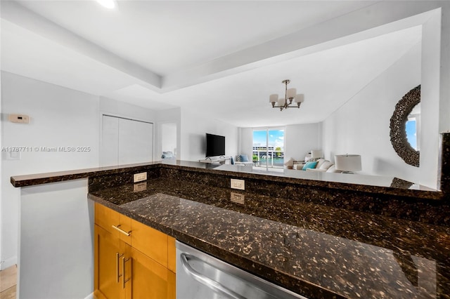 kitchen featuring dark stone countertops, open floor plan, and an inviting chandelier