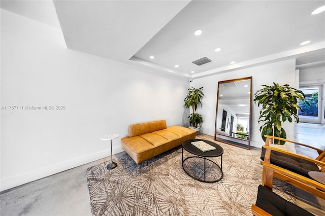 living area with recessed lighting, finished concrete floors, baseboards, visible vents, and a raised ceiling