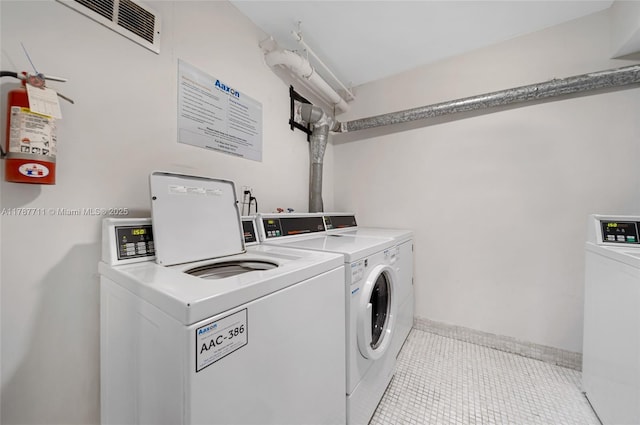 common laundry area featuring tile patterned floors, washing machine and clothes dryer, and baseboards