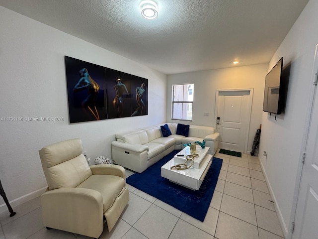 living area with baseboards, a textured ceiling, and light tile patterned flooring