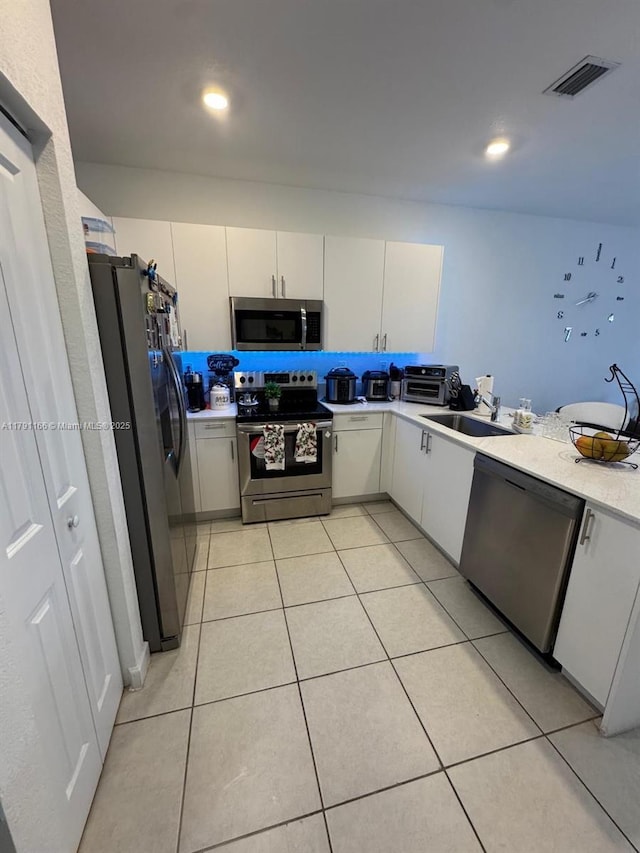 kitchen with stainless steel appliances, light countertops, a sink, white cabinetry, and visible vents