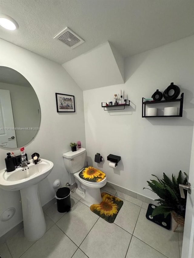 bathroom featuring tile patterned floors, toilet, visible vents, vaulted ceiling, and baseboards