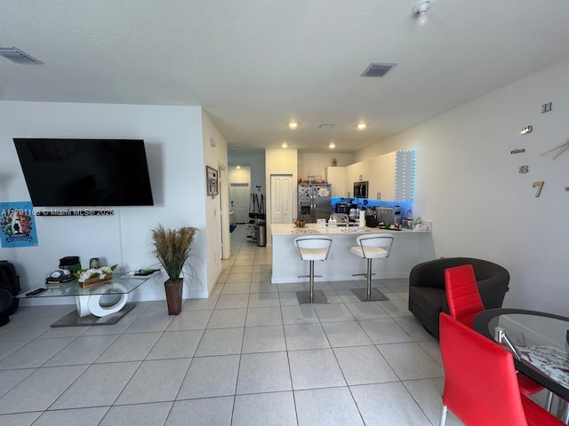 living area with light tile patterned floors, visible vents, and recessed lighting