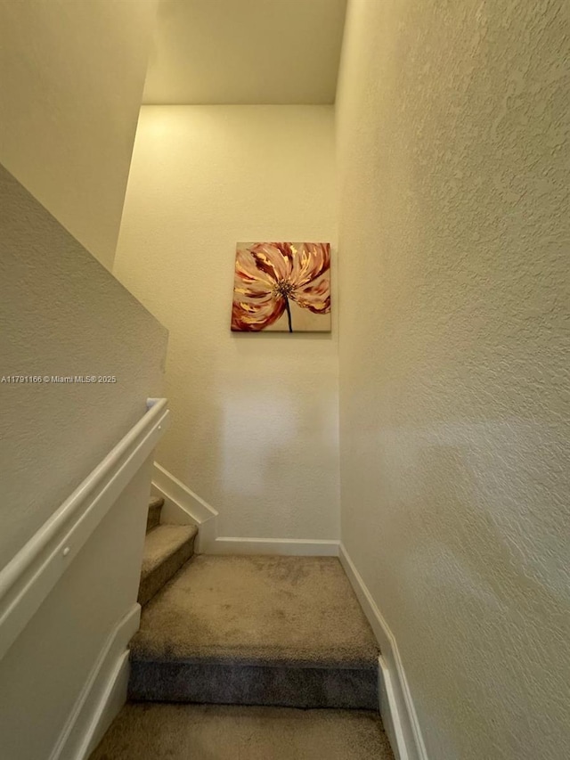 stairway featuring carpet flooring and baseboards