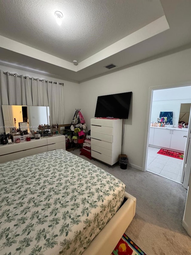 carpeted bedroom with a textured ceiling, visible vents, a tray ceiling, and baseboards